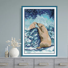 Load image into Gallery viewer, Framed cross-stitch art of two polar bears on a blue and white background, displayed on a gray surface with decorative items.