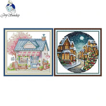 Load image into Gallery viewer, Two framed artworks of a store front and a snowy village scene, with 'Joy Sunday' logo.