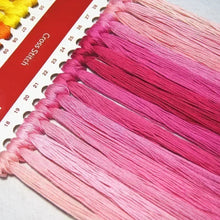 Load image into Gallery viewer, Collection of pink embroidery threads with a cross-stitch chart in the background
