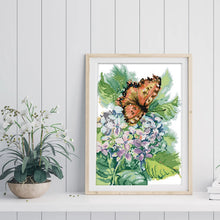 Load image into Gallery viewer, Framed cross-stitched artwork of a butterfly on flowers with a plant on a white surface.

