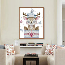 Load image into Gallery viewer, Framed cross-stitch art of a deer with a blue hat in a living room setting.
