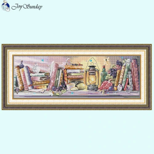 Vintage oil lamp and bookshelf still life cross stitch design on fabric.